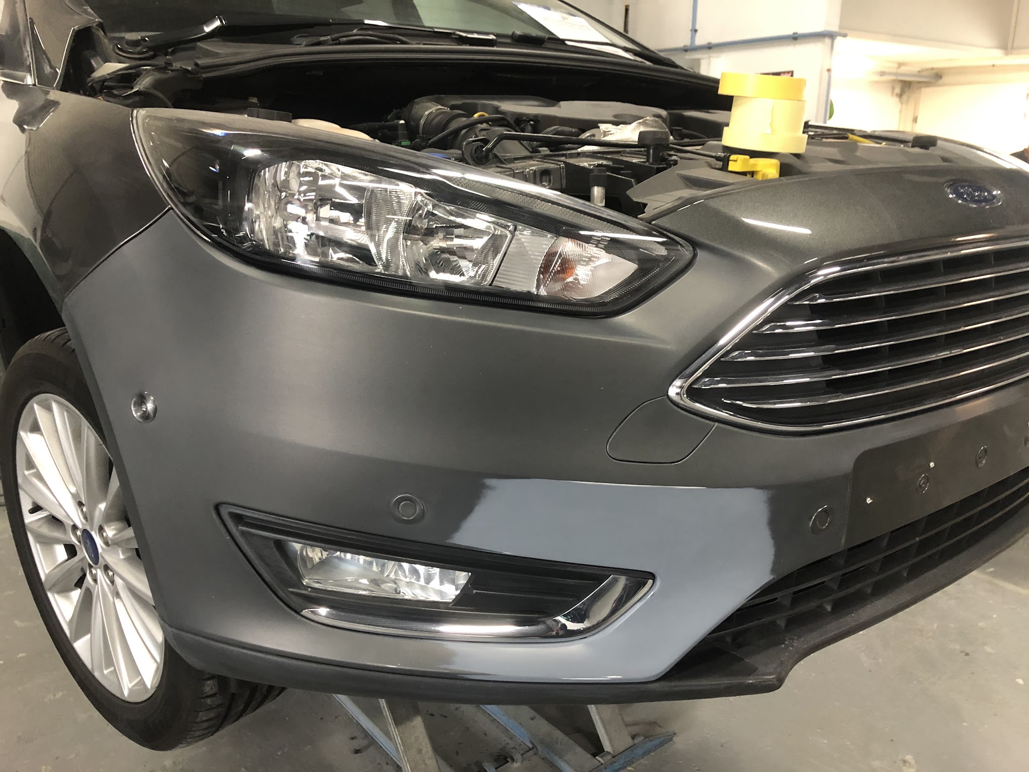 Grijze Ford Focus met de voorbumper in de grondlak en de motorkap open